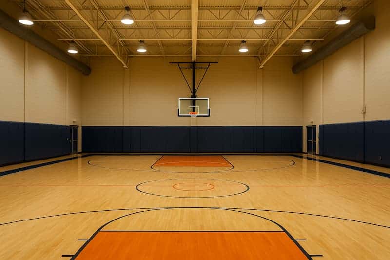 quadra de basquete coberta com piso de madeira polida e tabela centralizada