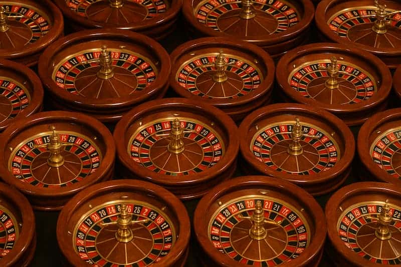 Múltiplas roletas de cassino em madeira alinhadas em série.